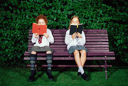 女学生在长凳上看书背景图片
