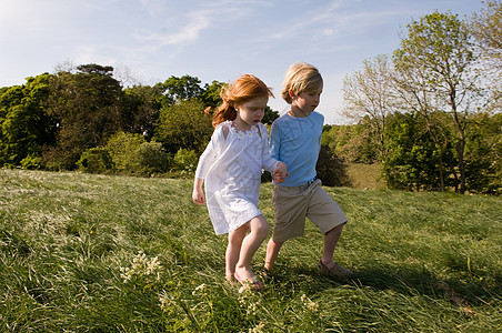 男孩和女孩在田里牵手玩耍的孩子背景