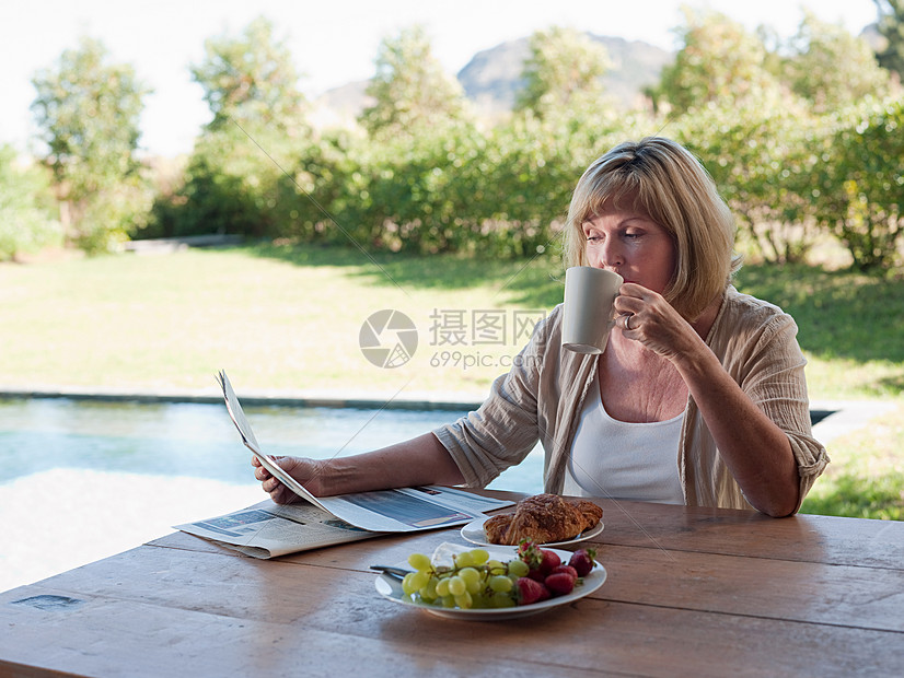 女人在户外看报喝咖啡