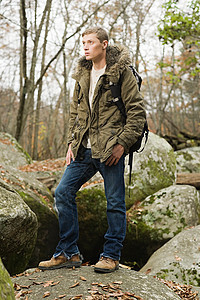 年轻人站在森林里的石头上图片