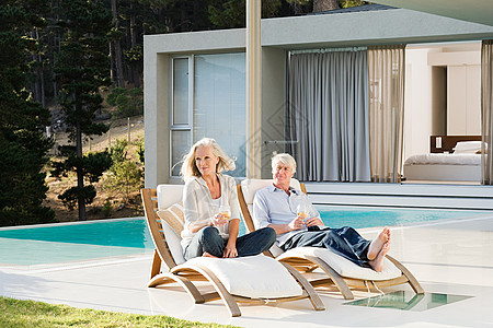 一对中年夫妇在泳池边的躺椅上休息图片