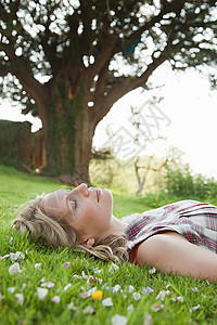 闭着眼睛躺在草地上的年轻女子图片