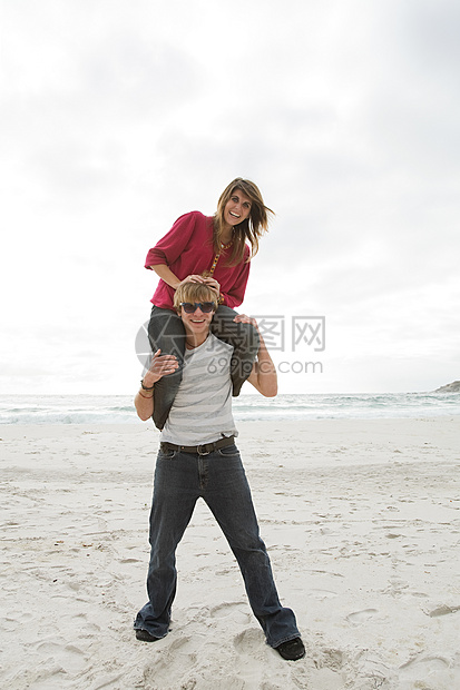 在海滩上背着女孩的年轻人图片