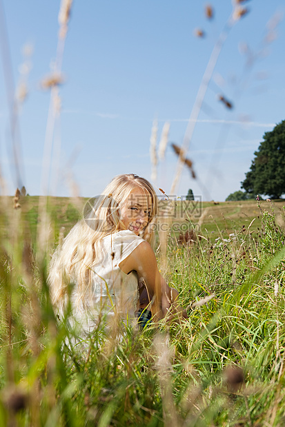 坐在田里对着镜头笑的年轻女人图片