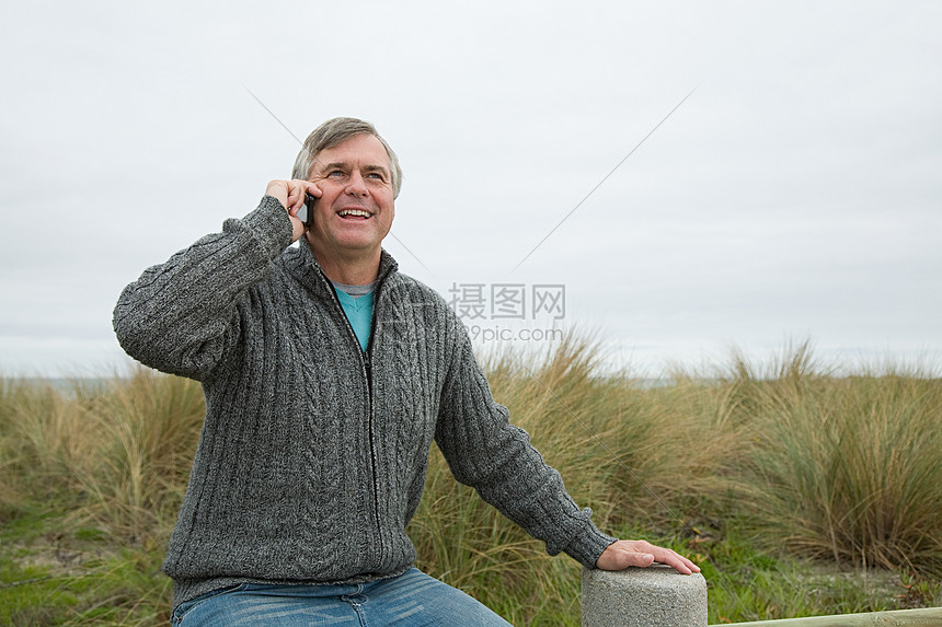 在海边拿着智能手机的男人图片