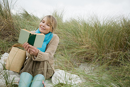 在沙丘上看书的女人图片