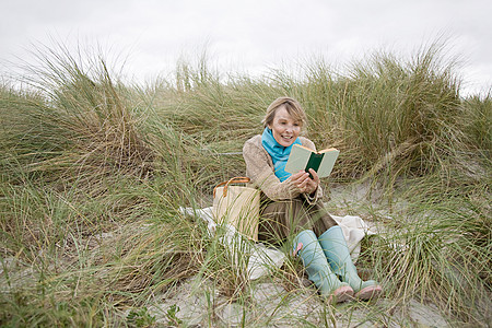 在沙丘上看书的女人图片