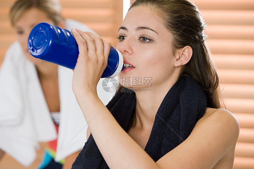在健身房喝水的女人