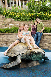 两个女孩坐在动物园乌龟雕像上图片