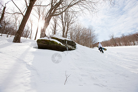 年轻人拿着滑雪板上山图片