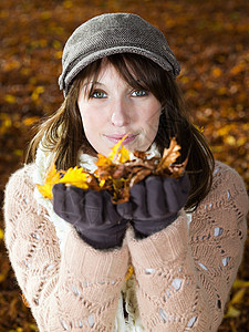 抱秋叶的年轻女子图片