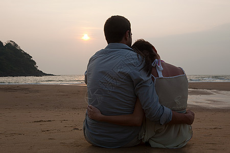 日落时分坐在海滩上的一对夫妇图片