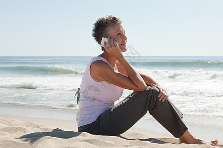在海滩上使用手机的老年妇女图片