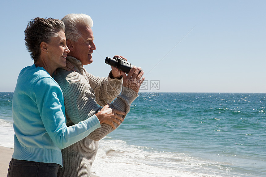 海滩上的一对成年夫妇带着望远镜图片