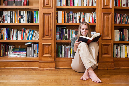 坐地板上坐在书架上看书的年轻女子背景