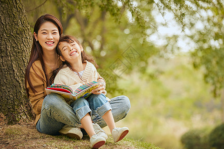 公园踏青温馨母女坐在树下读书背景