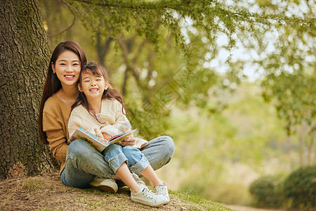 妈妈和女儿温馨母女坐在树下读书背景