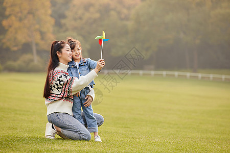 可爱母女草坪上玩风车背景