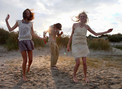 日落时分在海滩上跳舞的朋友图片