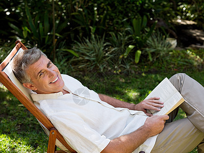 花园躺椅上看书的男人图片