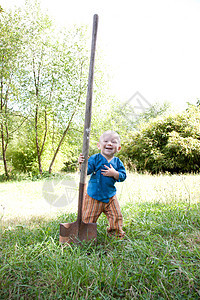 带着大铲子在花园里蹒跚学步的孩子图片