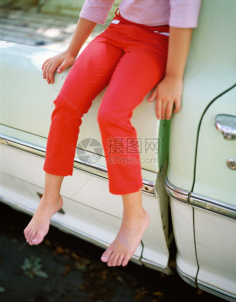 赤脚女孩穿着红色裤子坐在卡车上图片