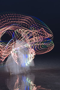 女人在夜晚跳舞时旋转发光的多色环箍图片