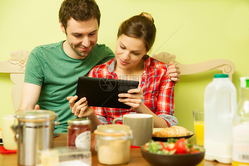 早餐时的年轻夫妇，使用数字平板电脑的女人图片
