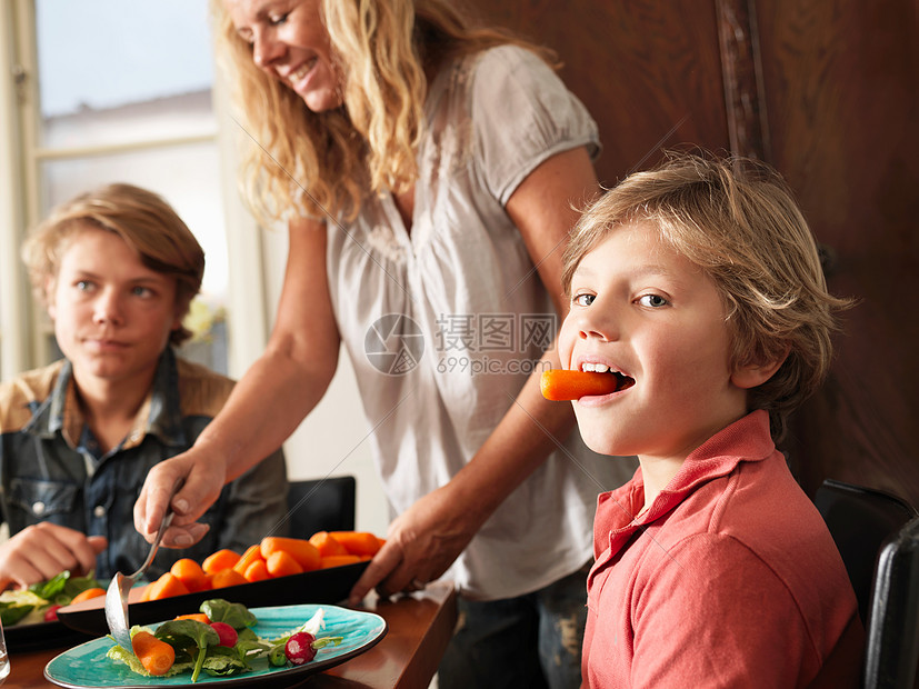 当妈妈端着胡萝卜吃健康餐的男孩图片