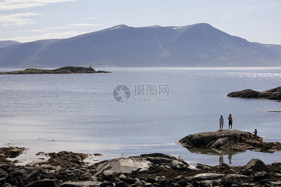 三个人站在挪威阿勒松峡湾岩石上图片