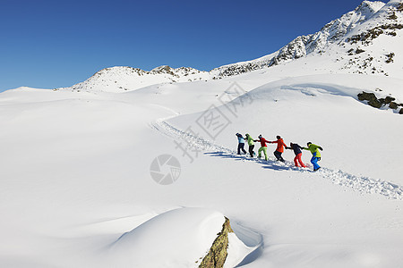 奥地利库赫泰朋友们在雪地里互相拉着上坡背景图片