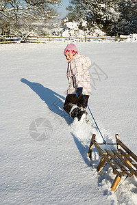 在雪地里拉雪橇的小女孩背景