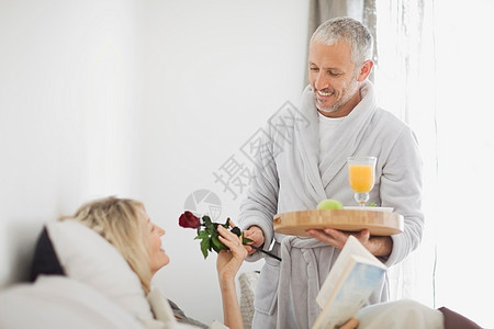 男子给床上的妻子带早餐与鲜花图片