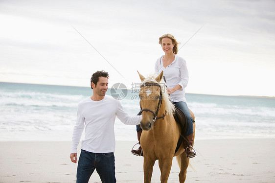 男人和女人在沙滩上骑马图片