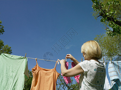 女人把衣服挂在晾衣绳上图片