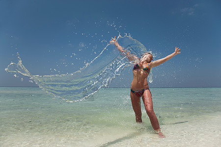 在海滩上泼水的女人图片