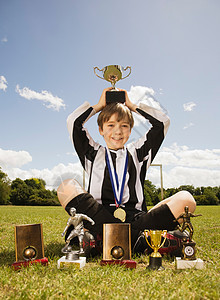 获得奖杯和奖牌的男孩足球运动员图片