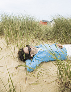 戴着太阳镜躺在沙丘上的女人休闲高清图片素材