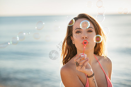 意大利撒丁岛卡斯蒂达斯海滩上吹泡泡的年轻女人的肖像图片