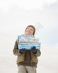 男孩拿着圣诞礼物在雪地里图片