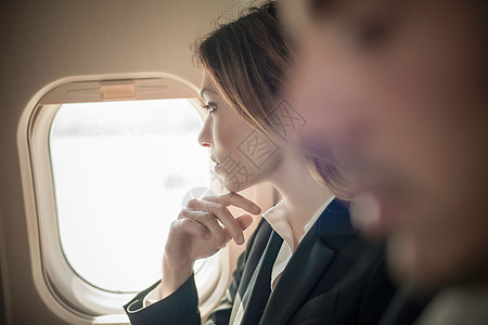 从飞机窗口向外看的女乘客背景图片