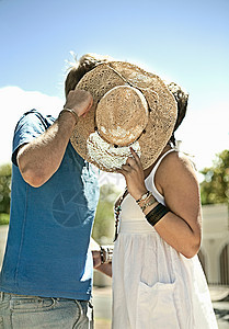 公园里的一对情侣在遮阳帽后面接吻图片