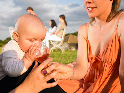 婴儿用母亲的杯子喝水图片