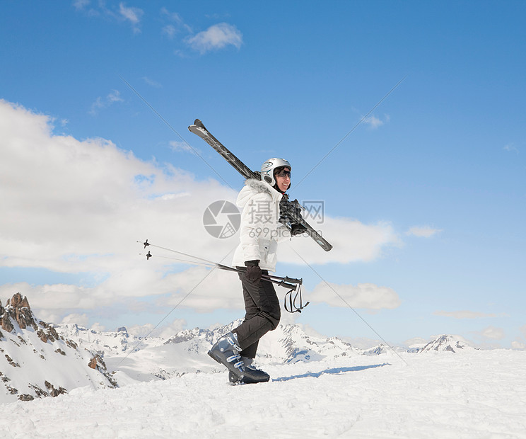 女人带着滑雪板在雪地里上山图片