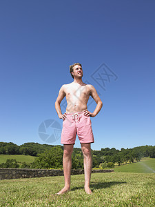阳光下的草地穿着泳衣的年轻人背景