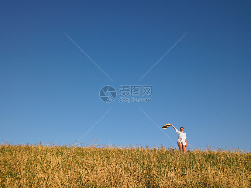 在田里挥舞帽子的女人图片