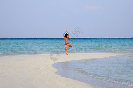 在热带海滩上练习瑜伽的女人图片