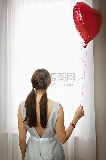 在窗户前拿着气球的女人图片
