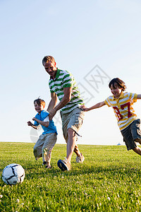 父亲和两个儿子踢足球图片