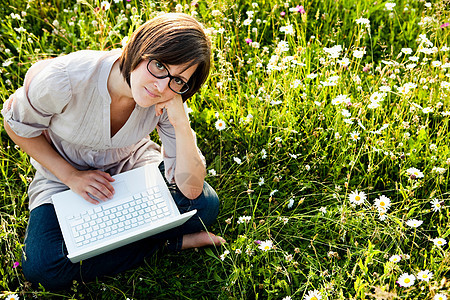 带笔记本电脑的女人在荒野草地图片